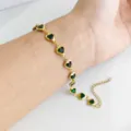 Dettaglio ravvicinato di un bracciale in acciaio inossidabile dorato con cuori verdi - Verde scuro
