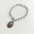 Detail shot of a stainless steel ball bead bracelet with a religious saint pendant. - Saint Francis Portrait