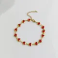 High quality detail view of golden stainless steel anklet featuring vibrant red heart charms - Red