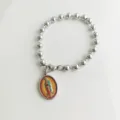 Dettaglio di un bracciale a sfere in acciaio inox con ciondolo religioso della Vergine Maria. - Ritratto della Vergine Maria