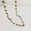 Primo piano di un'elegante collana in acciaio dorato con cristalli verdi a rombo. - 42+5cm / Verde Scuro