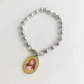Dettaglio ravvicinato di un bracciale a sfere in acciaio con ciondolo di Gesù ovale. - Ritratto di Gesù