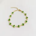 Detailed view of gold stainless steel bracelet with vivid green heart-shaped stones. - Yellow-Green