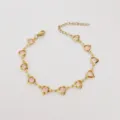 Nahaufnahme eines goldenen Edelstahlarmbands mit facettierten rosa Herzglassteinen - 17+5cm / Lotosrosa