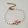 Primo piano del braccialetto di perle in acciaio con ciondolo a forma di margherita - Colore acciaio / Rosa