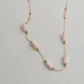 Macro detail of a gold stainless steel chain necklace with pink bamboo-joint beads. - Gold / Lotus Pink