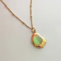 Detailed macro view of a vintage 18K gold plated necklace featuring a green cat eye pendant. - Light Green