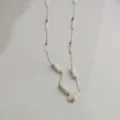 Close-up detail of a minimalist stainless steel chain with white bamboo-style segments - Gold / Milky White