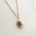 Close-up of a retro 18K gold-plated necklace with a deep blue oval stone pendant - Navy Blue