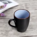 Matte black ceramic coffee mug featuring a light blue interior and elegant brown rim - Dark Blue