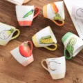 Vue détaillée de tasses en céramique avec illustrations de légumes dessinées à la main. - Mug 300ml / Motif Racine de Lotus