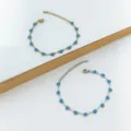 Close-up of gold and silver stainless steel bracelets with blue enamel heart charms. - Teal
