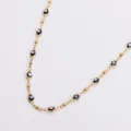 Close-up of gold stainless steel Hamsa hand necklace with black enamel evil eye charms. - Black