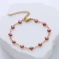 Detailed view of a gold stainless steel bracelet with red evil eye enamel charms. - Red
