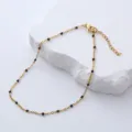 Detalle de tobillera de acero dorado con cuentas de esmalte negro sobre soporte de piedra - 23+3cm / Negro