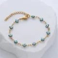 Close-up of gold stainless steel bracelet with square blue evil eye enamel charms - Emerald