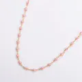 Close-up detail of a minimalist golden stainless steel necklace with pink evil eye beads - Pink