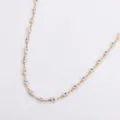 Dettaglio dei ciondoli malocchio e mano di Fatima in smalto su collana in acciaio dorato. - Oro / Bianco