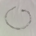 Dettaglio di un bracciale a catena a graffetta in acciaio inossidabile argento su tessuto. - 21.5cm / Colore acciaio