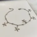 Dettaglio della cavigliera in acciaio inossidabile con ciondoli a forma di stella marina - Colore acciaio