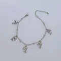 Primo piano ravvicinato di cavigliera in acciaio inox con ciondoli a delfino - 23+5cm / Colore acciaio