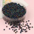 Iridescent metallic glass seed beads for DIY jewelry making, scattered on pink background - Mineral Green