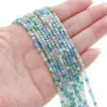 Hand holding strands of mixed blue and green faceted square glass beads for DIY jewelry - 2mm (Approx. 180 Pcs/Strand) / Forest Lake