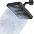 Close-up detail of a matte black 6-inch square shower head with powerful water spraying - Square Black With Shower Arm