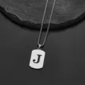 Detailed macro shot of stainless steel pendant with letter J cutout on box chain - Letter J