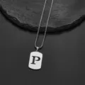 Detailed macro shot of a stainless steel rectangular tag necklace with letter P cutout - Letter P