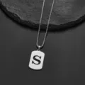 Close-up detail of a minimalist stainless steel dog tag necklace with cutout letter S - Letter S