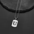 Macro detail of silver stainless steel pendant featuring a cutout letter U on box chain - Letter U