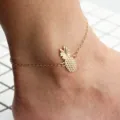 Elegant gold-colored pineapple pendant anklet for women on a white tile background - Hand and foot back chain pineapple