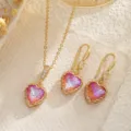 Makrodetail eines goldenen Schmucksets mit rosa Herz-Zirkonia und Retro-Spitzenrand - Mit Titanstahlkette (3-teiliges Set) / Gradient Orange