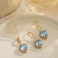 Detailansicht des blauen Herz-Zirkonia-Schmucksets mit goldenen Spitzenkanten. - Mit Titanstahlkette (3-teiliges Set) / Verlauf Blau