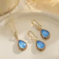Detailed close-up of bridal jewelry set with blue teardrop stones and gold finish - Teardrop Pendant / Blue
