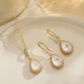 Close-up of teardrop bridal jewelry set featuring iridescent stones and gold filigree. - Teardrop Pendant / White