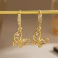 Detailed macro shot of gold-plated butterfly earrings featuring pink cubic zirconia - Hollow Butterfly (80491) / Earrings / Pink