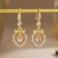 Detailed macro view of gold-plated bow earrings featuring a pink heart-shaped zircon center - Bow Knot Heart (80493) / Earrings / Pink