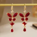 Detailed view of vintage gold butterfly earrings featuring faceted red zircon stones. - Hook Earrings Style (80490) / Red