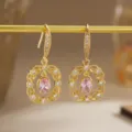 A detailed macro view of gold-plated earrings with pink zircon and filigree work - Retro Round Style (80496) / Pink