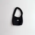 Detailed macro view of a black handmade style knitted handbag with white egg logo tag. - 19*14 / Dark Gray
