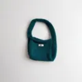 Detail showing the soft knit texture and logo tag of the teal handbag - 19*14 / Green