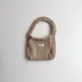 Detailopname van een gezellige beige gebreide polstas met een klein 'egg.'-label - 19*14 / Licht kaki