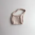 Detailopname van een beige gebreide polstas met een minimalistisch 'egg.' label - 19*14 / Beige