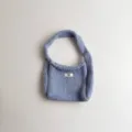 Detailed macro view of a light blue knitted mini handbag with white 'egg.' label on front - 19*14 / Light Blue