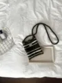 Nahaufnahme einer handgestrickten Mini-Umhängetasche in Dunkelgrün und Weiß auf einem Bett - 14*19.5 / Grün