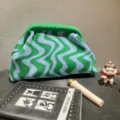Detailed shot of green and blue wavy striped knitted pouch bag displayed with props - Mint Green/Blue