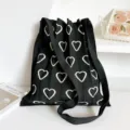 Dettaglio della borsa a tracolla in maglia plissettata nera con motivo a cuore bianco e trama. - Cuore