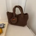 Detailopname van de textuur van een bruine handgemaakte gehaakte handtas met mini-zakje. - Koffie